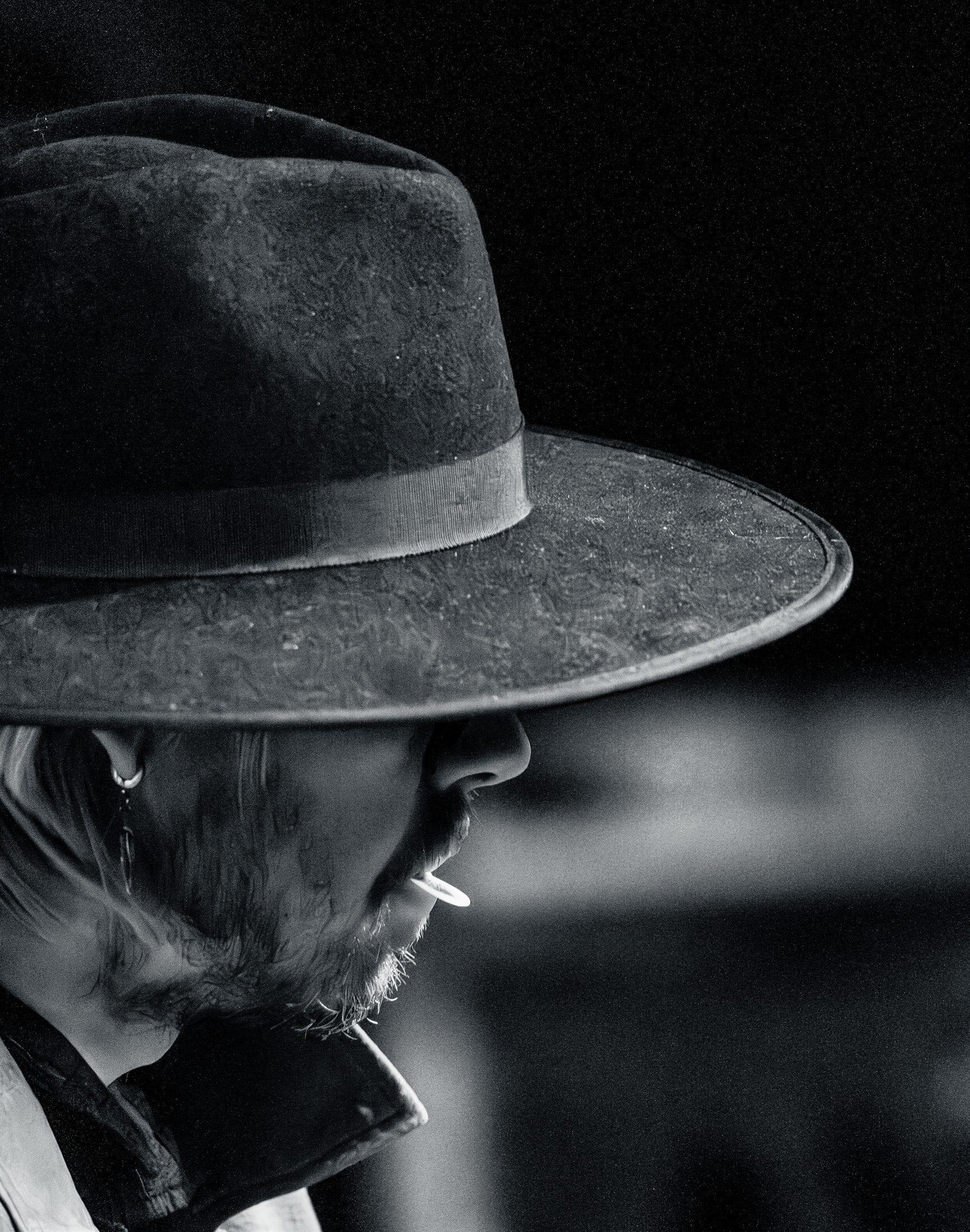 Black and white profile of a performer under a wide brimmed hat